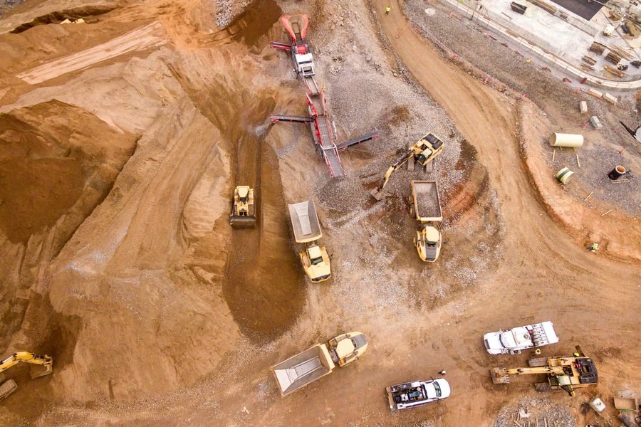 A mine site seen from directly above, haul trucks and dozers working the pit.